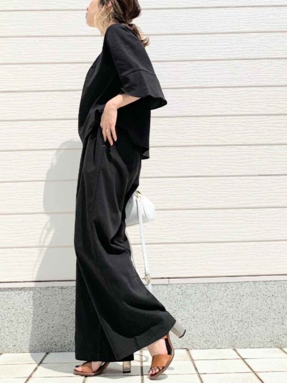 ホワイト系のショルダーバッグ、ブラウン系のサンダル、ブラック系のその他パンツを着用したレディースの春コーディネートの2枚目の写真