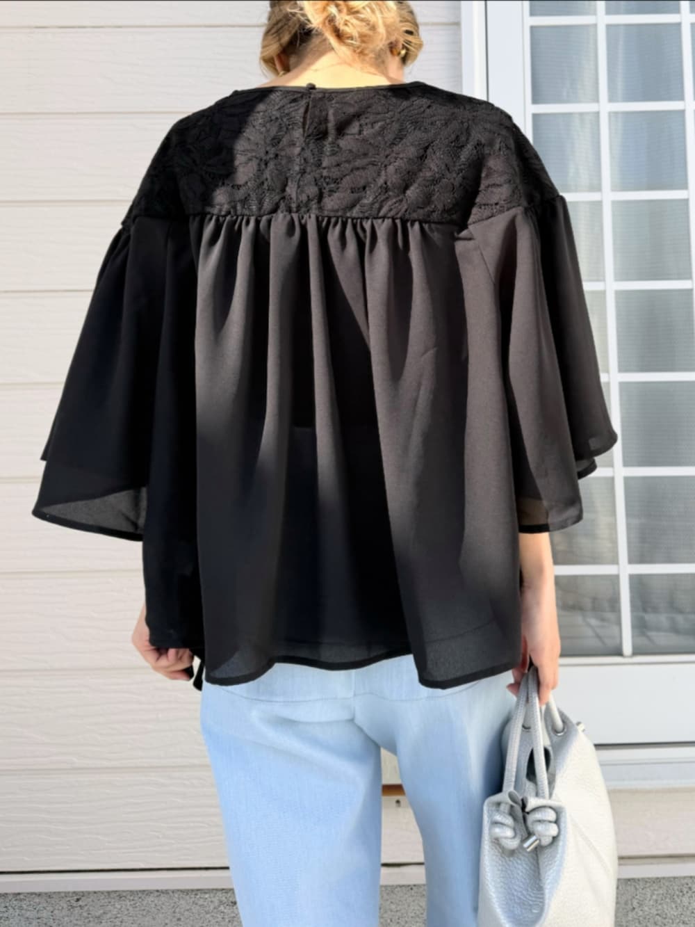 ブルー系のデニムパンツ、シルバー系のトートバッグ、ブラック系のシャツ/ブラウスを着用したレディースの春コーディネートの5枚目の写真