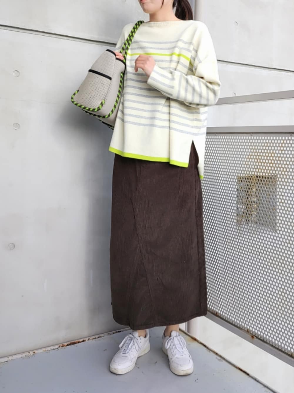 グレー系のトートバッグ、ブラウン系のスカート、ホワイト系のスニーカーを着用したレディースの冬コーディネートの2枚目の写真