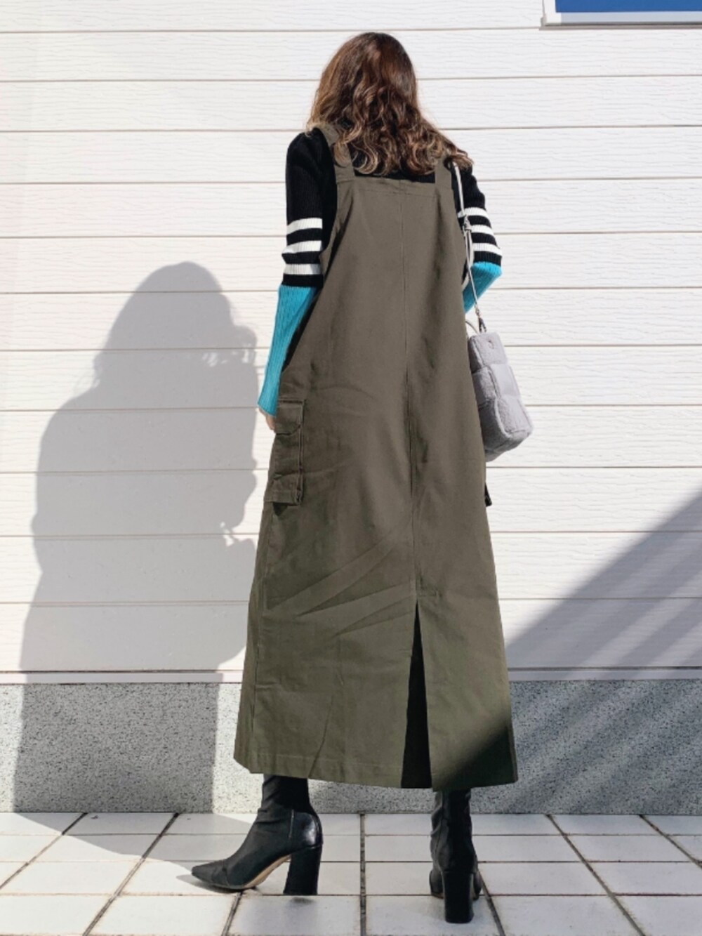 ブラック系のニット/セーター、グレー系のショルダーバッグ、グリーン系のジャンパースカートを着用したレディースの秋コーディネートの3枚目の写真