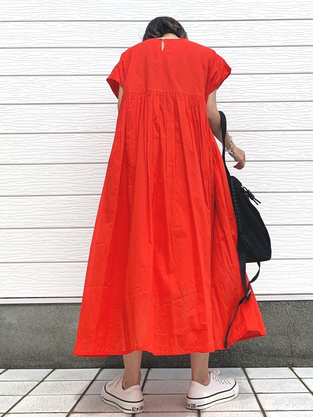 ブラック系のトートバッグ、レッド系のワンピース、ホワイト系のスニーカーを着用したレディースの春コーディネートの3枚目の写真