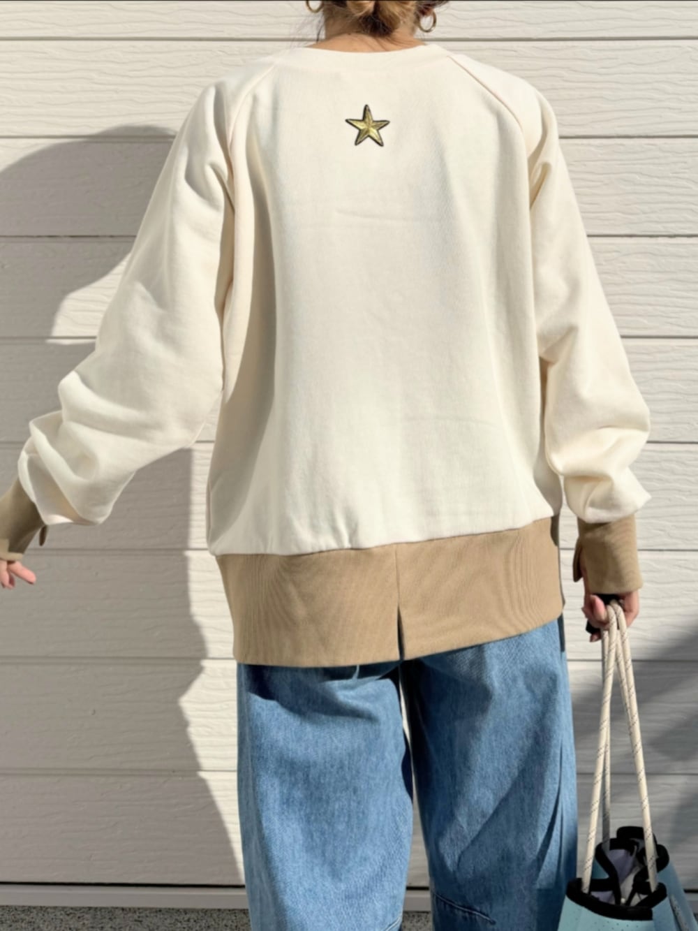 ブルー系のトートバッグ、ブルー系のデニムパンツ、ベージュ系のスウェットを着用したレディースの冬コーディネートの5枚目の写真