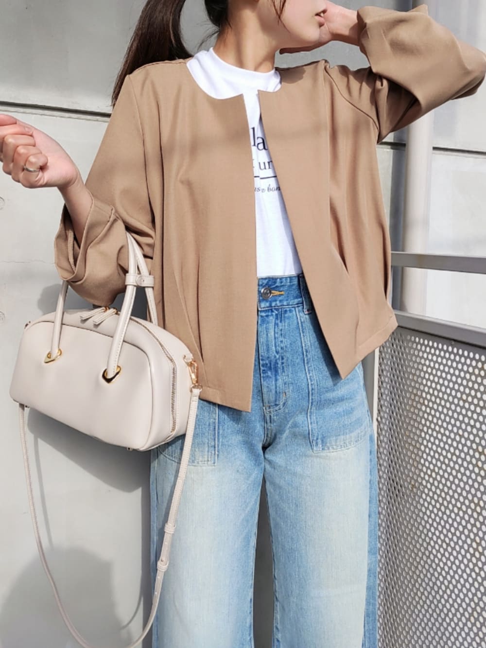 ブルー系のデニムパンツ、ホワイト系のスニーカー、ホワイト系のボストンバッグを着用したレディースの冬コーディネートの3枚目の写真
