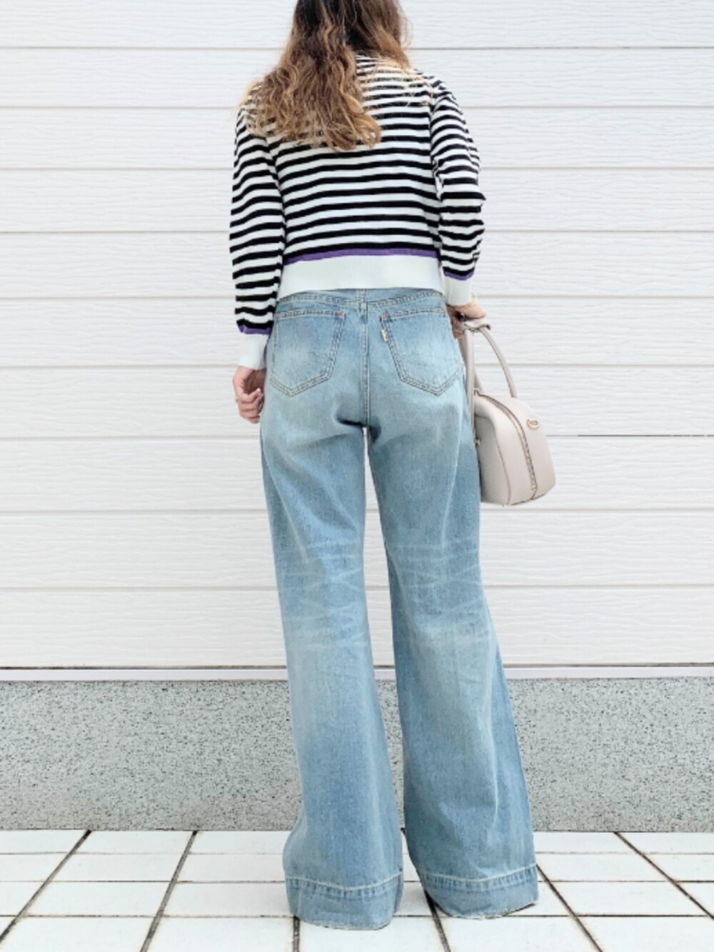 ブルー系のデニムパンツ、ホワイト系のボストンバッグ、ホワイト系のカーディガン/ボレロを着用したレディースの夏コーディネートの3枚目の写真