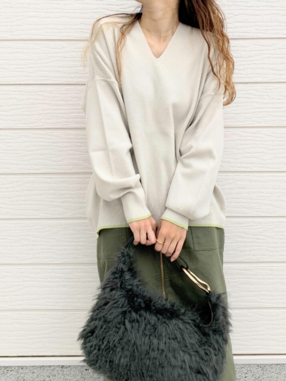 グリーン系のスカート、グレー系のハンドバッグ、グレー系のニット/セーターを着用したレディースの秋コーディネートの4枚目の写真