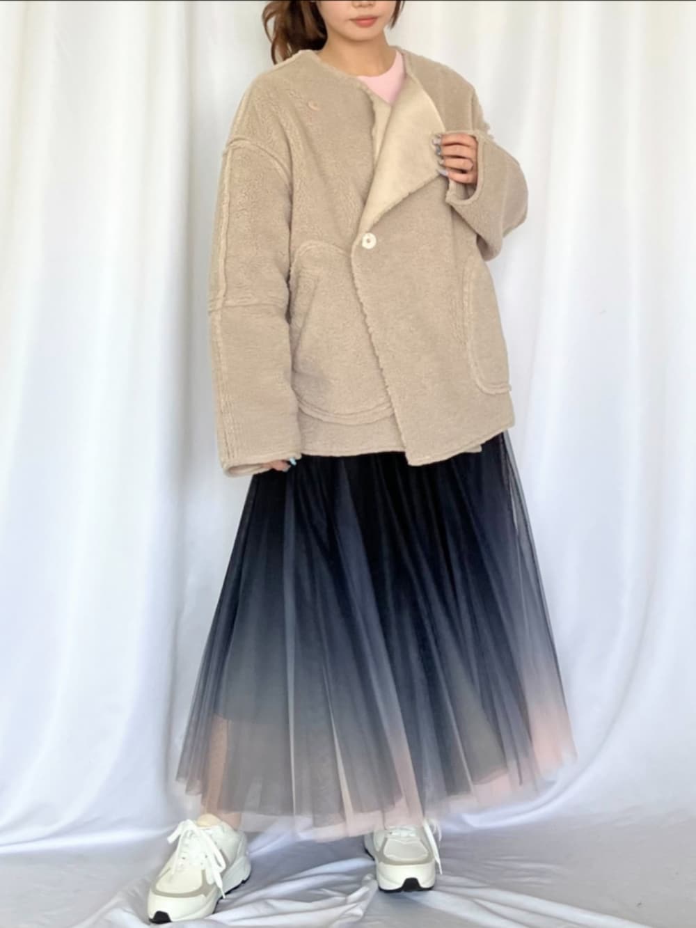 ブラック系のスカート、ホワイト系のスニーカー、ベージュ系のブルゾンを着用したレディースの冬コーディネートの2枚目の写真