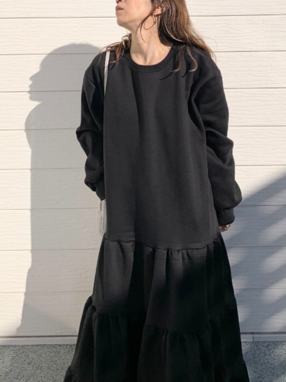 グレー系のショルダーバッグ、ホワイト系のスニーカー、ブラック系のワンピースを着用したレディースの冬コーディネートの5枚目の写真