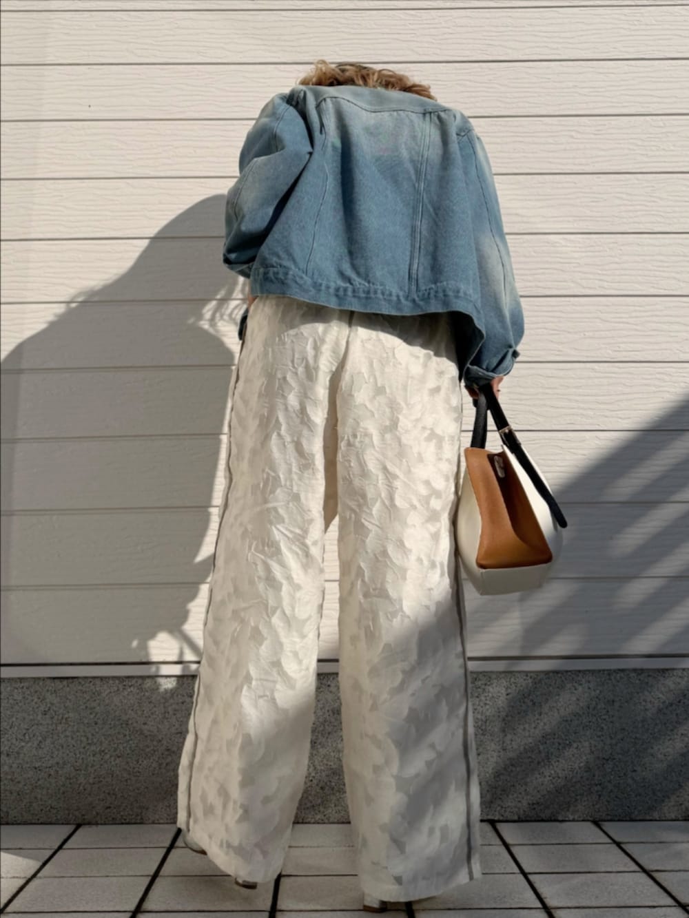 ブルー系のデニムジャケット、ホワイト系のトートバッグ、ホワイト系のTシャツ/カットソーを着用したレディースの冬コーディネートの3枚目の写真