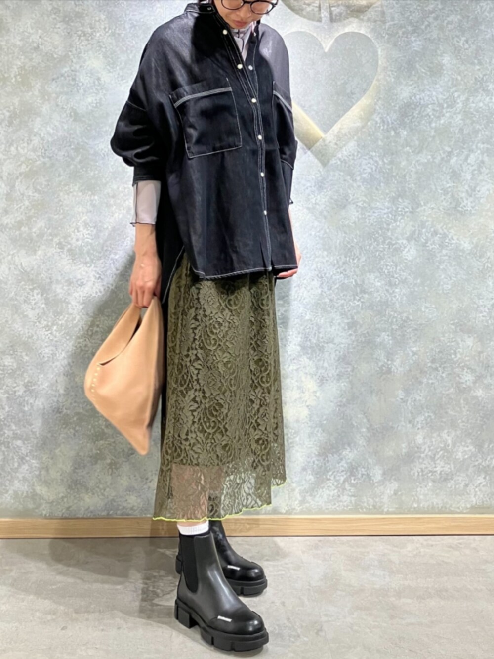 ブラック系のブーツ、グリーン系のスカート、ベージュ系のトートバッグを着用したレディースの秋コーディネートの2枚目の写真