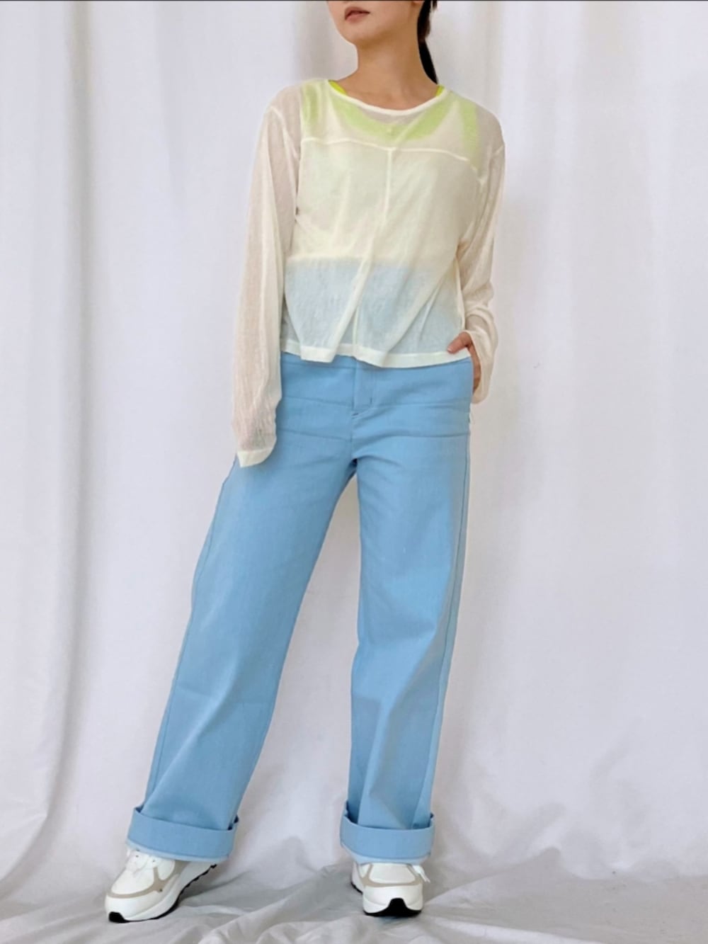 ブルー系のデニムパンツ、ホワイト系のスニーカー、ホワイト系のタンクトップを着用したレディースの冬コーディネートの3枚目の写真