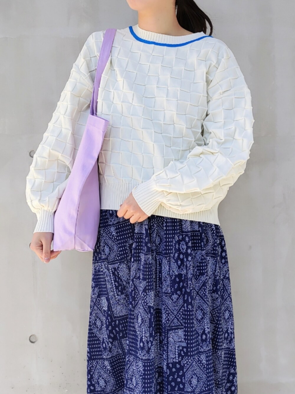 パープル系のトートバッグ、ホワイト系のニット/セーター、ホワイト系のスニーカーを着用したレディースの冬コーディネートの3枚目の写真