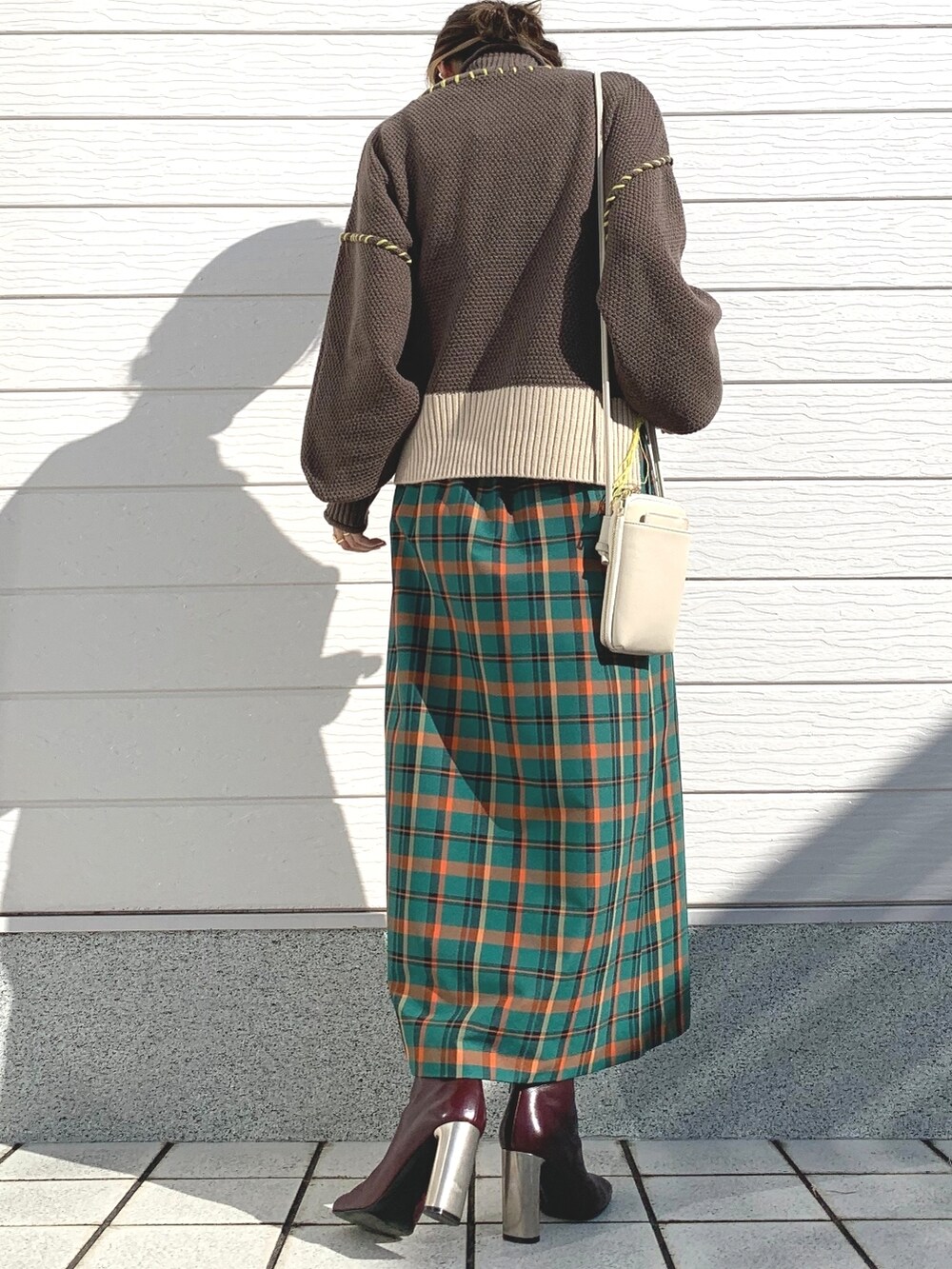 ブラウン系のニット/セーター、グリーン系のスカート、ブラウン系のブーツを着用したレディースの秋コーディネートの3枚目の写真