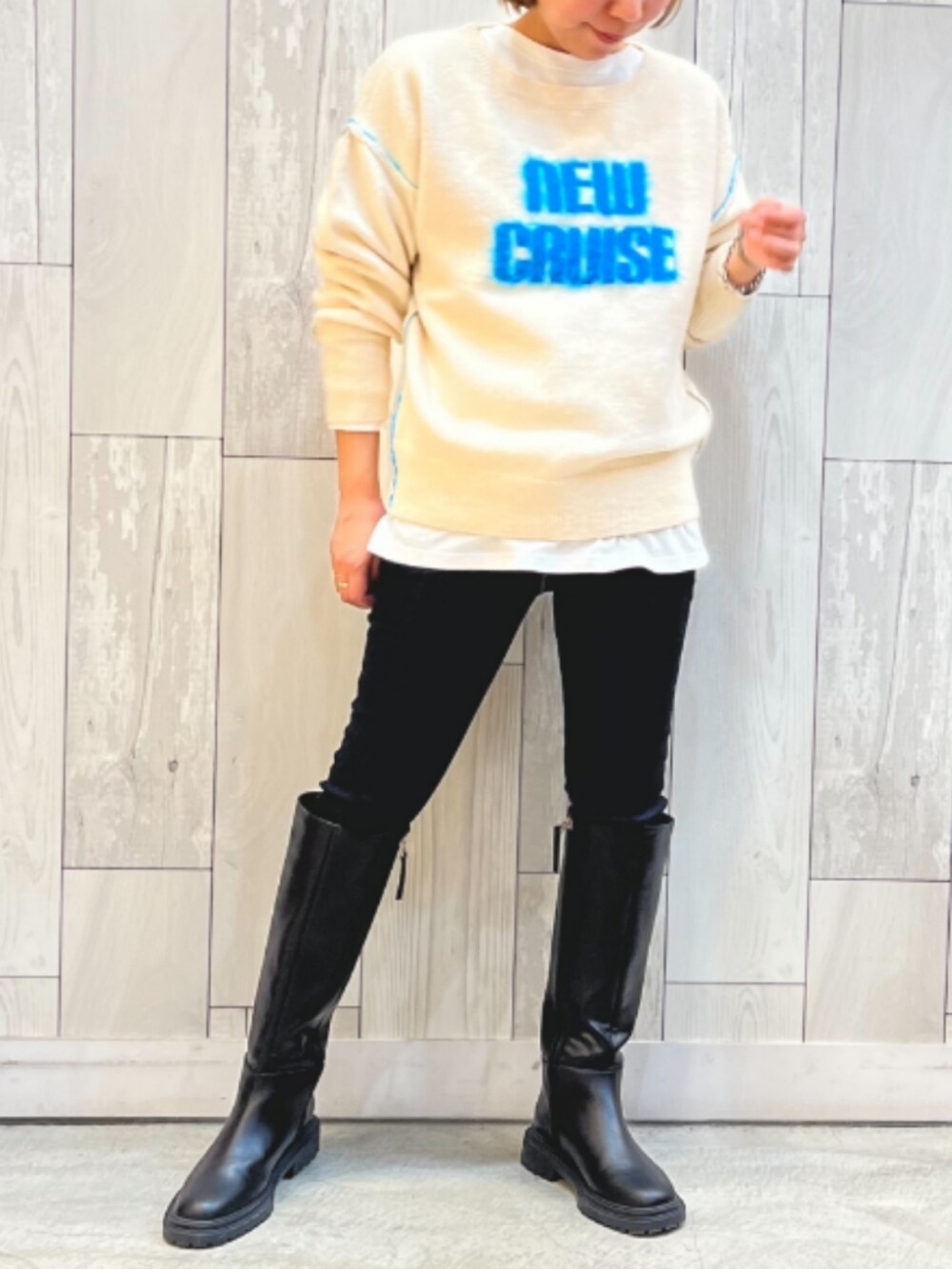 ブラック系のブーツ、ブルー系のデニムパンツ、ホワイト系のニット/セーターを着用したレディースの冬コーディネートの2枚目の写真