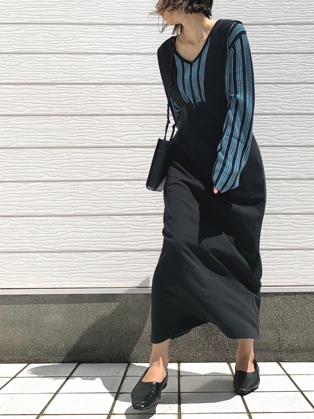 ブラック系のショルダーバッグ、ブルー系のニット/セーター、ブラック系のジャンパースカートを着用したレディースの夏コーディネートの3枚目の写真