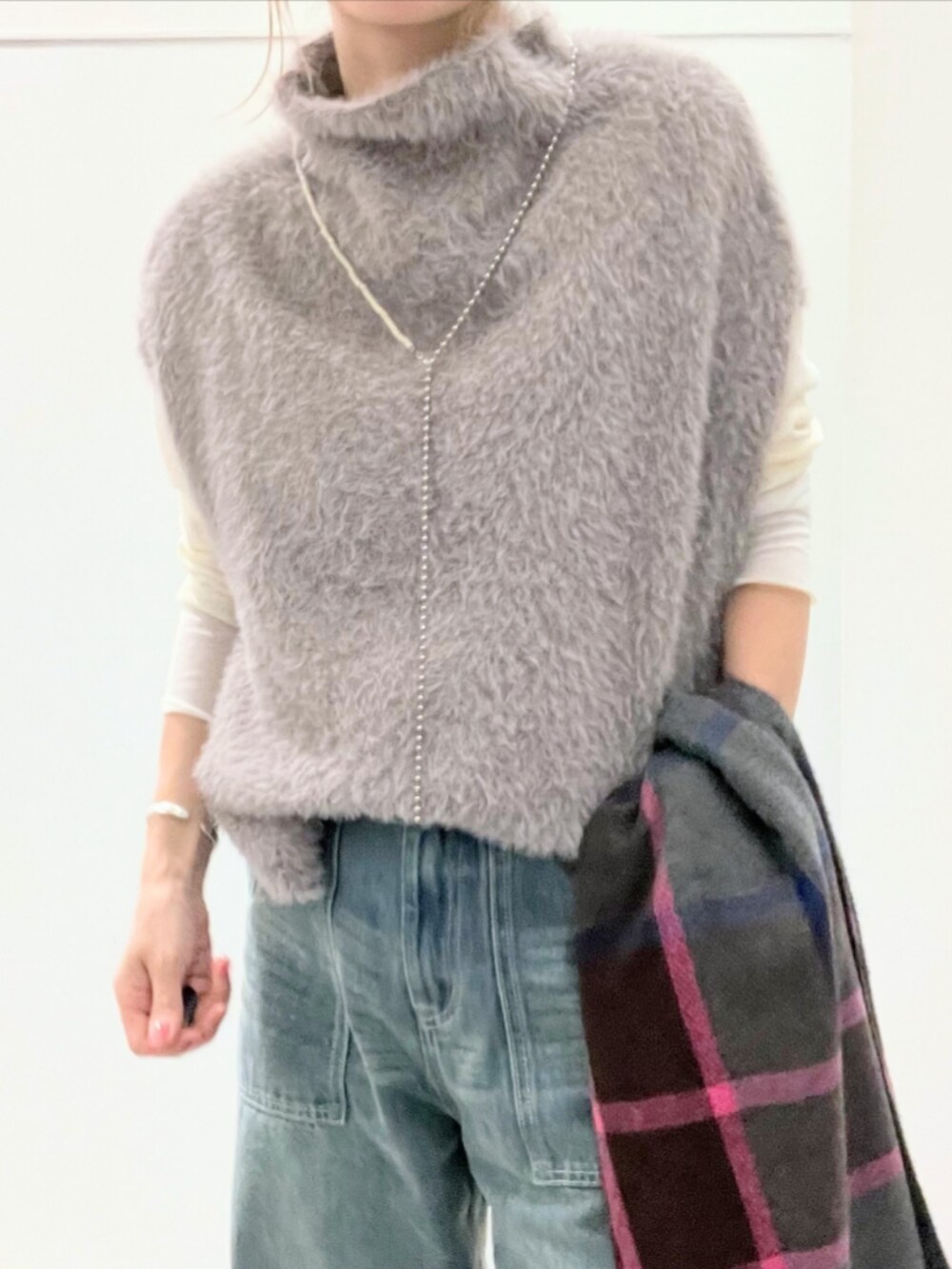ブルー系のデニムパンツ、グレー系のベスト、ベージュ系のTシャツ/カットソーを着用したレディースの秋コーディネートの4枚目の写真