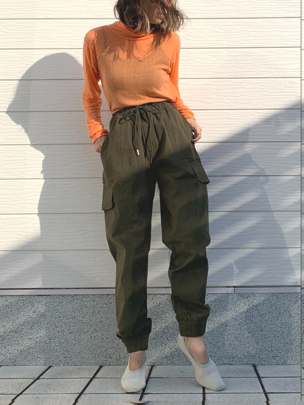 グリーン系のその他パンツ、ホワイト系のショルダーバッグ、オレンジ系のTシャツ/カットソーを着用したレディースの冬コーディネートの4枚目の写真
