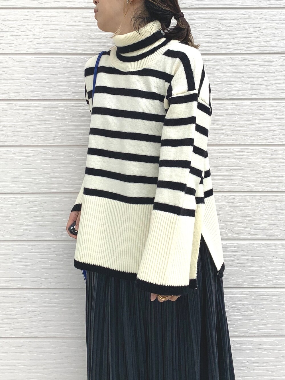 シルバー系のスニーカー、ブルー系のショルダーバッグ、ホワイト系のニット/セーターを着用したレディースの秋コーディネートの4枚目の写真