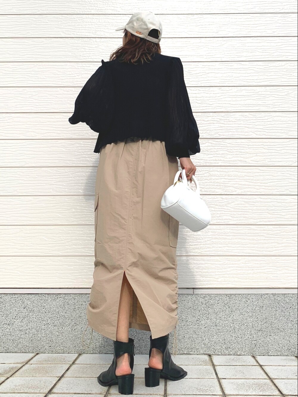 ブラック系のサンダル、ベージュ系のスカート、ブラック系のカーディガン/ボレロを着用したレディースの春コーディネートの2枚目の写真