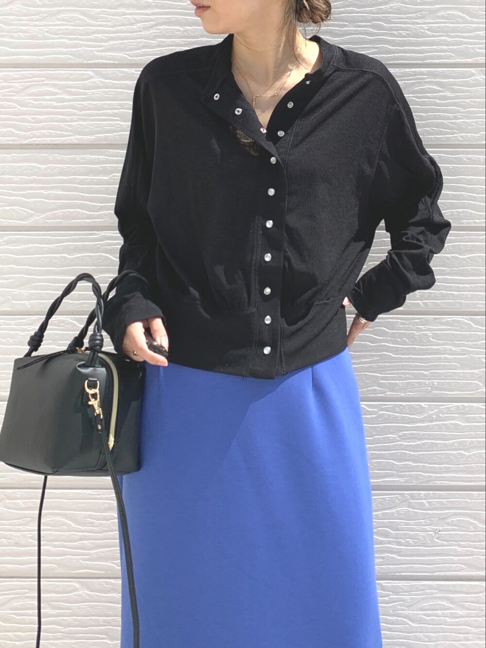 シルバー系のスニーカー、ブルー系のスカート、ブラック系のハンドバッグを着用したレディースの春コーディネートの4枚目の写真