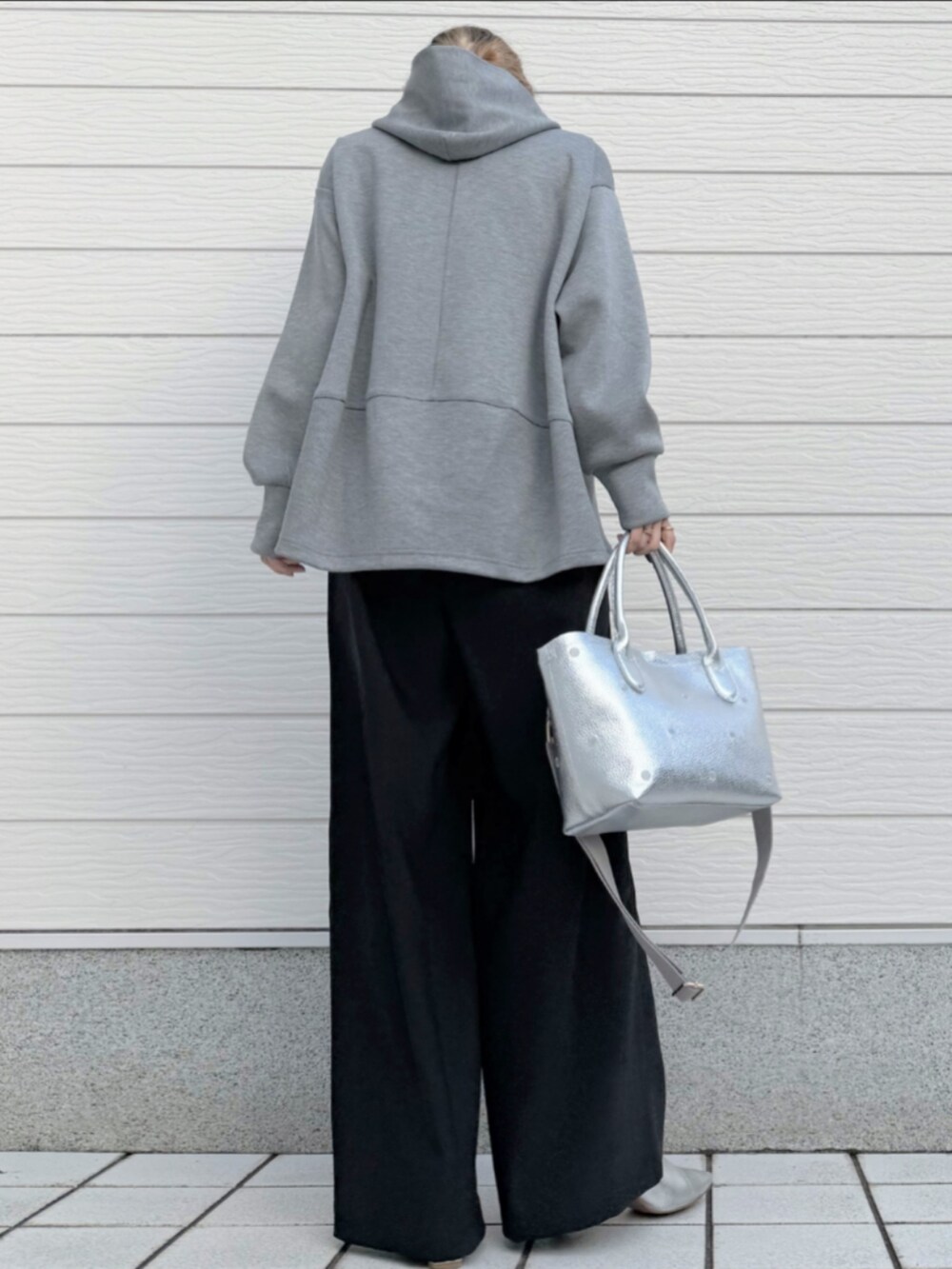 シルバー系のトートバッグ、ブラック系のその他パンツ、グレー系のパーカーを着用したレディースの冬コーディネートの3枚目の写真