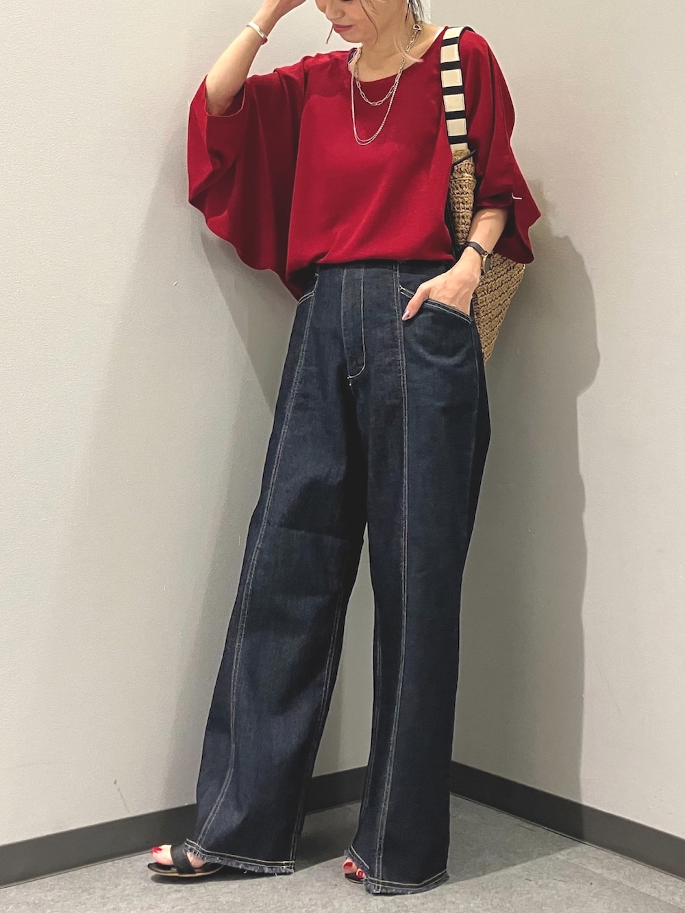 ブルー系のデニムパンツ、レッド系のシャツ/ブラウス、グリーン系のトートバッグを着用したレディースの夏コーディネートの4枚目の写真