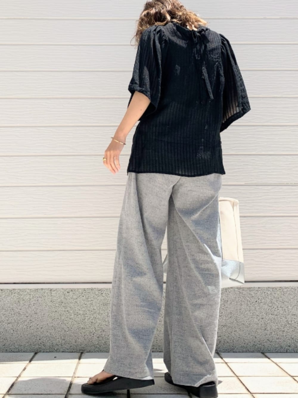 グレー系のその他パンツ、ブラック系のシャツ/ブラウス、シルバー系のハンドバッグを着用したレディースの春コーディネートの2枚目の写真