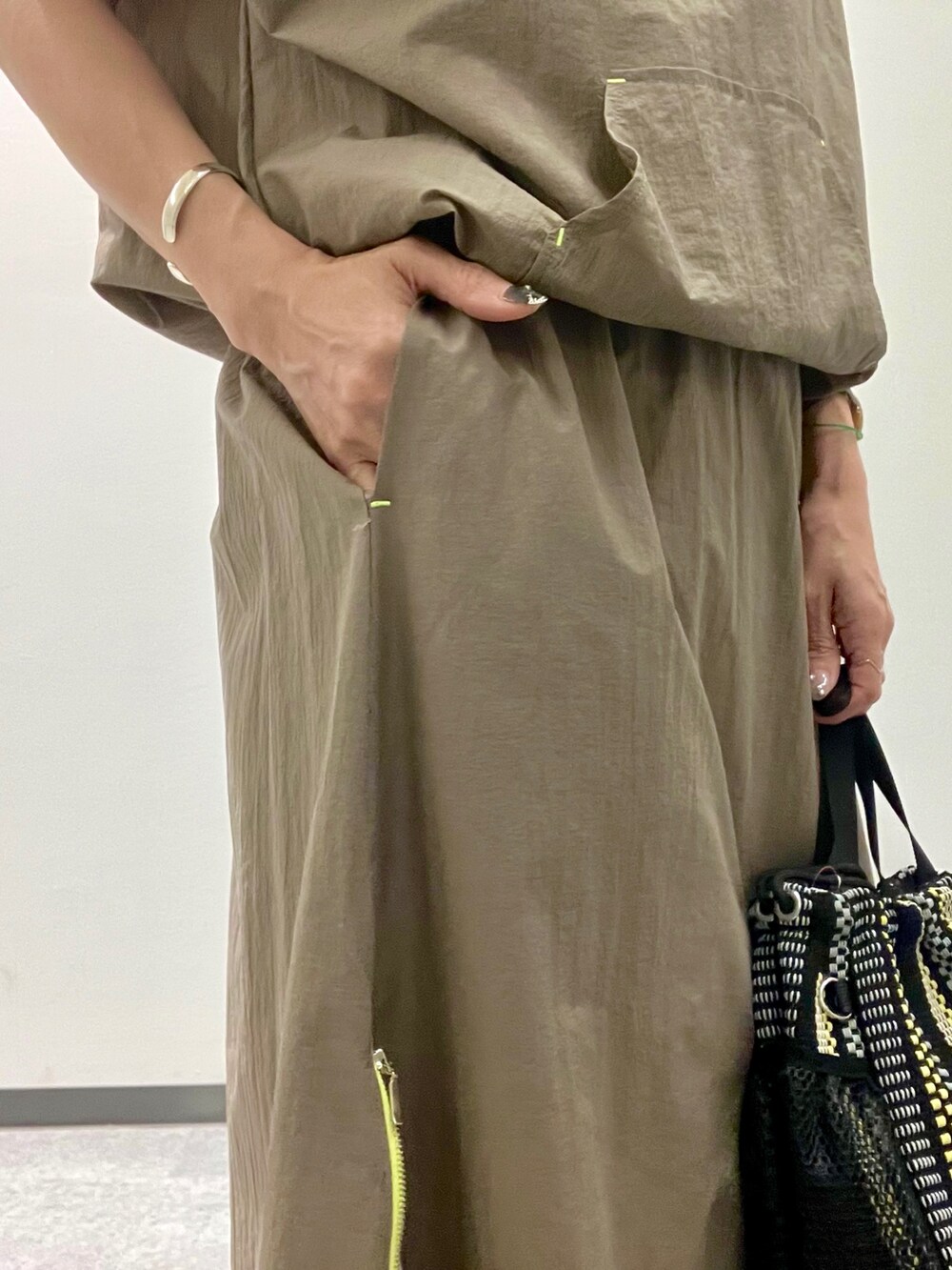 グリーン系のパーカー、グリーン系のスカート、ブラック系のトートバッグを着用したレディースの夏コーディネートの5枚目の写真