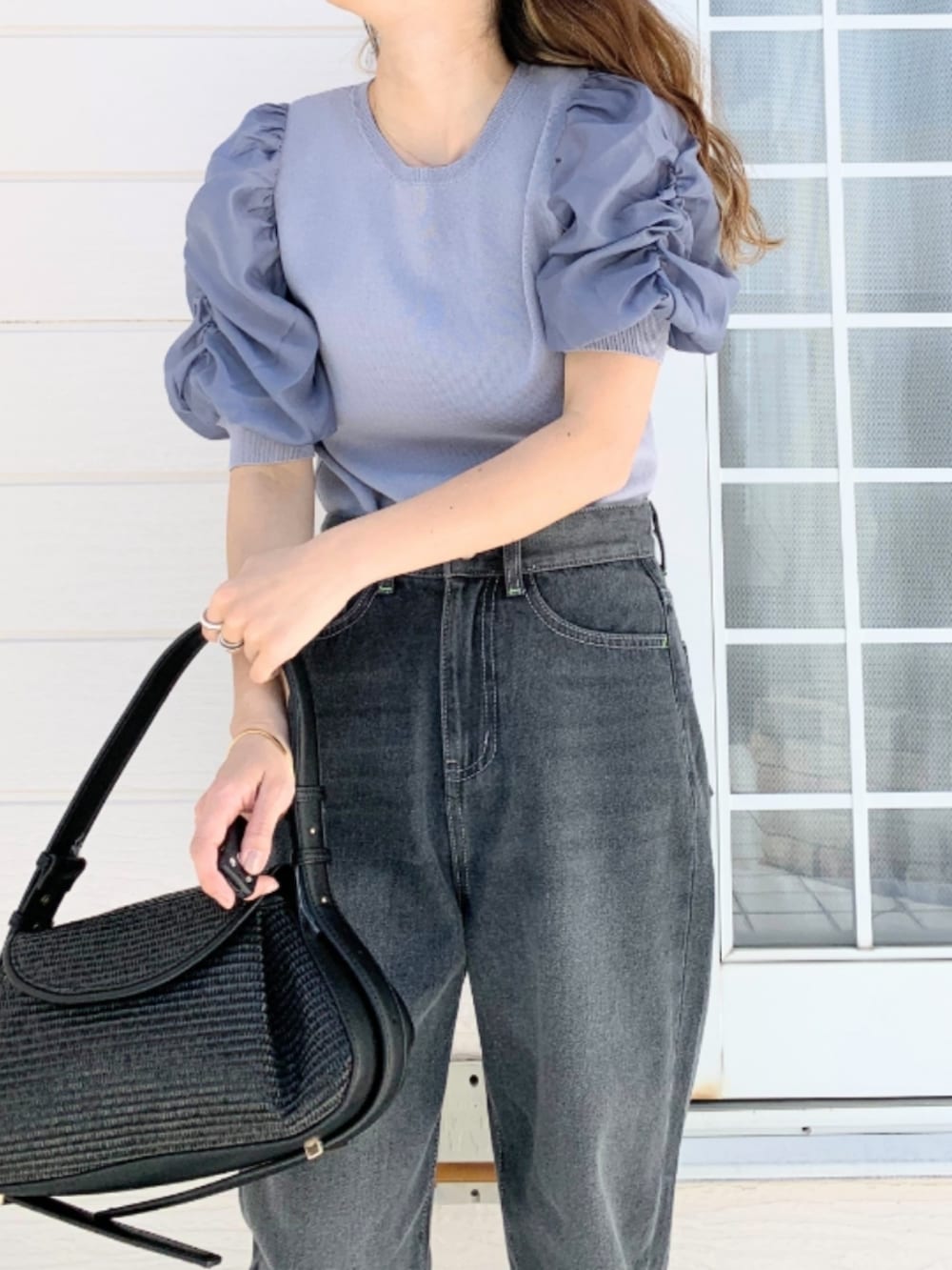 グレー系のデニムパンツ、ブラック系のショルダーバッグ、ブルー系のニット/セーターを着用したレディースの春コーディネートの4枚目の写真