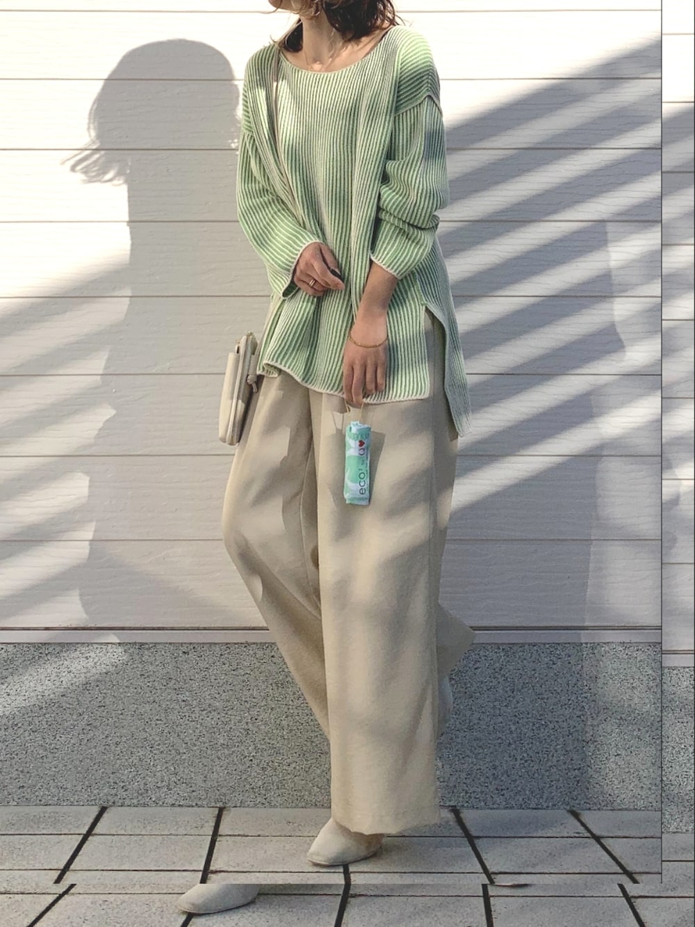 ベージュ系のその他パンツ、グリーン系のニット/セーター、ホワイト系のショルダーバッグを着用したレディースの冬コーディネートの3枚目の写真