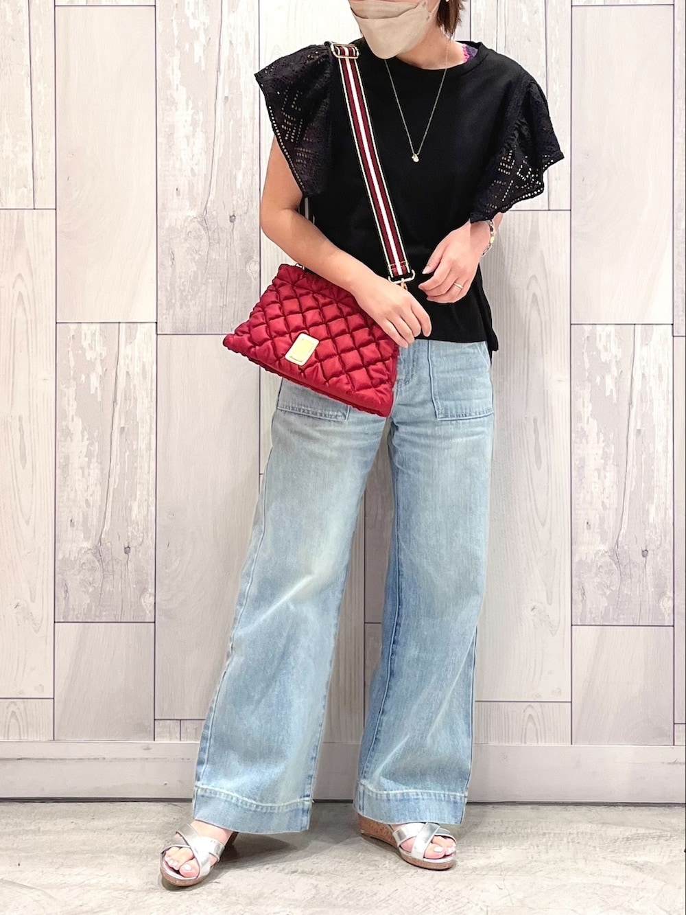 ブルー系のデニムパンツ、シルバー系のサンダル、レッド系のショルダーバッグを着用したレディースの夏コーディネートの2枚目の写真