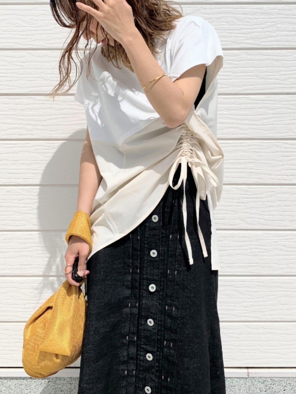 ブラック系のデニムスカート、ブラック系のサンダル、イエロー系のショルダーバッグを着用したレディースの春コーディネートの3枚目の写真