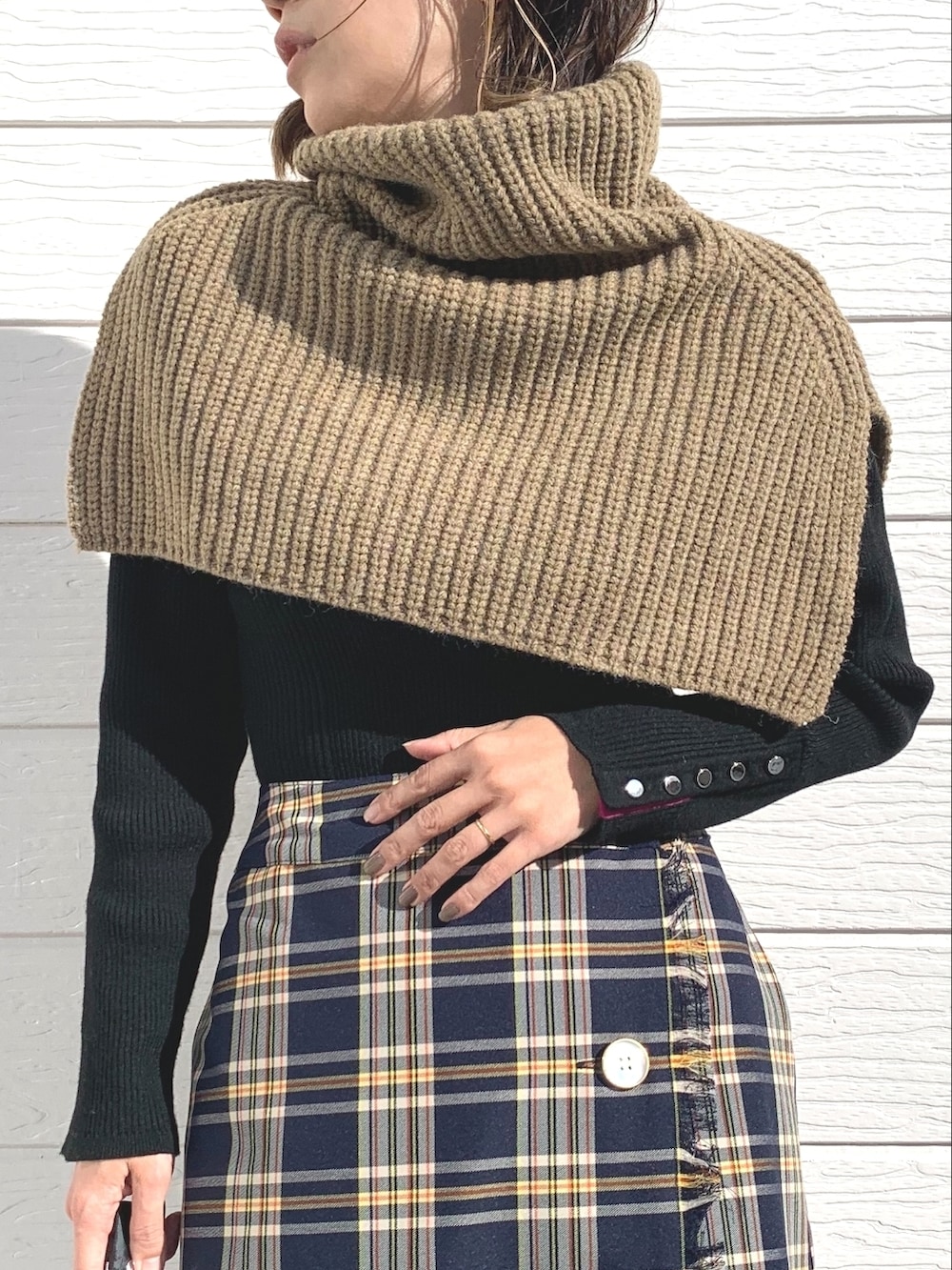 ブルー系のスカート、ブラック系のニット/セーター、ベージュ系のネックウォーマー/スヌードを着用したレディースの秋コーディネートの3枚目の写真