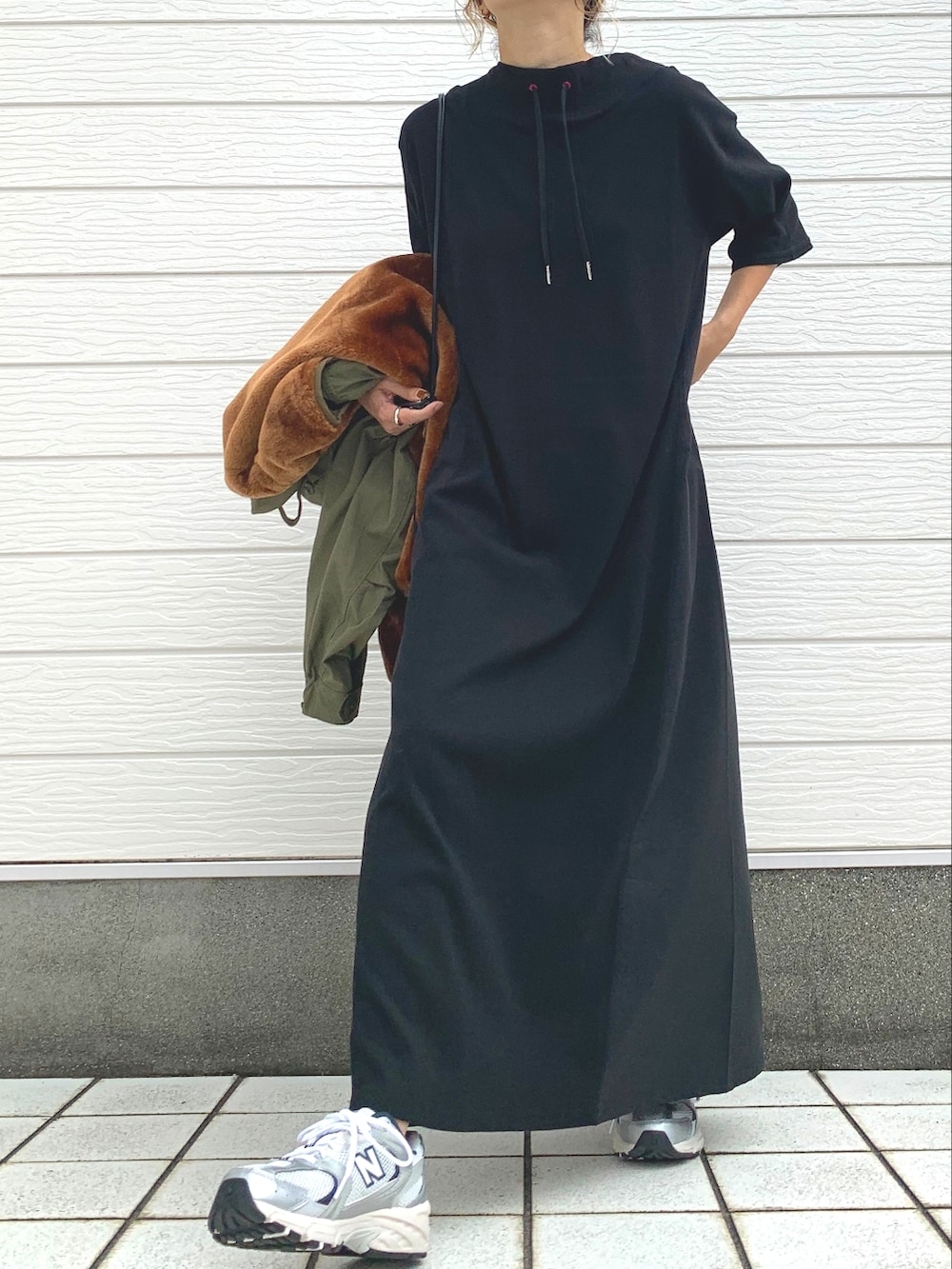 シルバー系のスニーカー、ブラック系のワンピース、グリーン系のモッズコートを着用したレディースの秋コーディネートの2枚目の写真