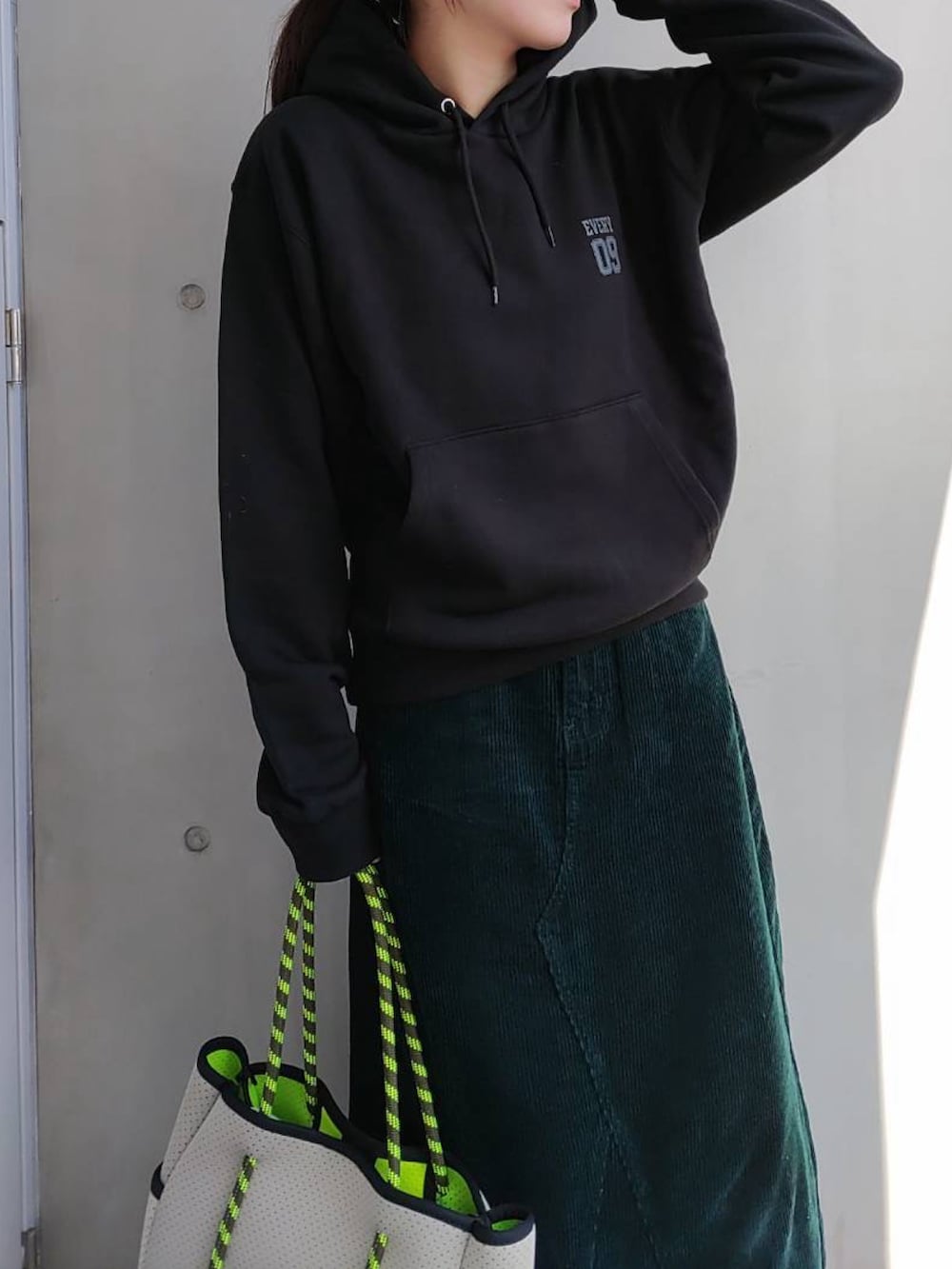 グリーン系のスカート、グレー系のトートバッグ、ブラック系のスニーカーを着用したレディースの冬コーディネートの3枚目の写真