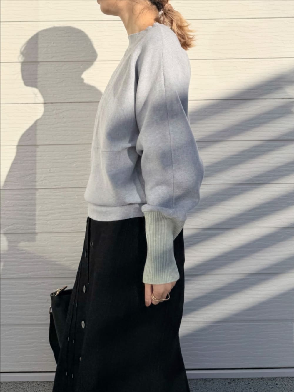 ブラック系のデニムスカート、ブラック系のトートバッグ、グレー系のニット/セーターを着用したレディースの冬コーディネートの4枚目の写真