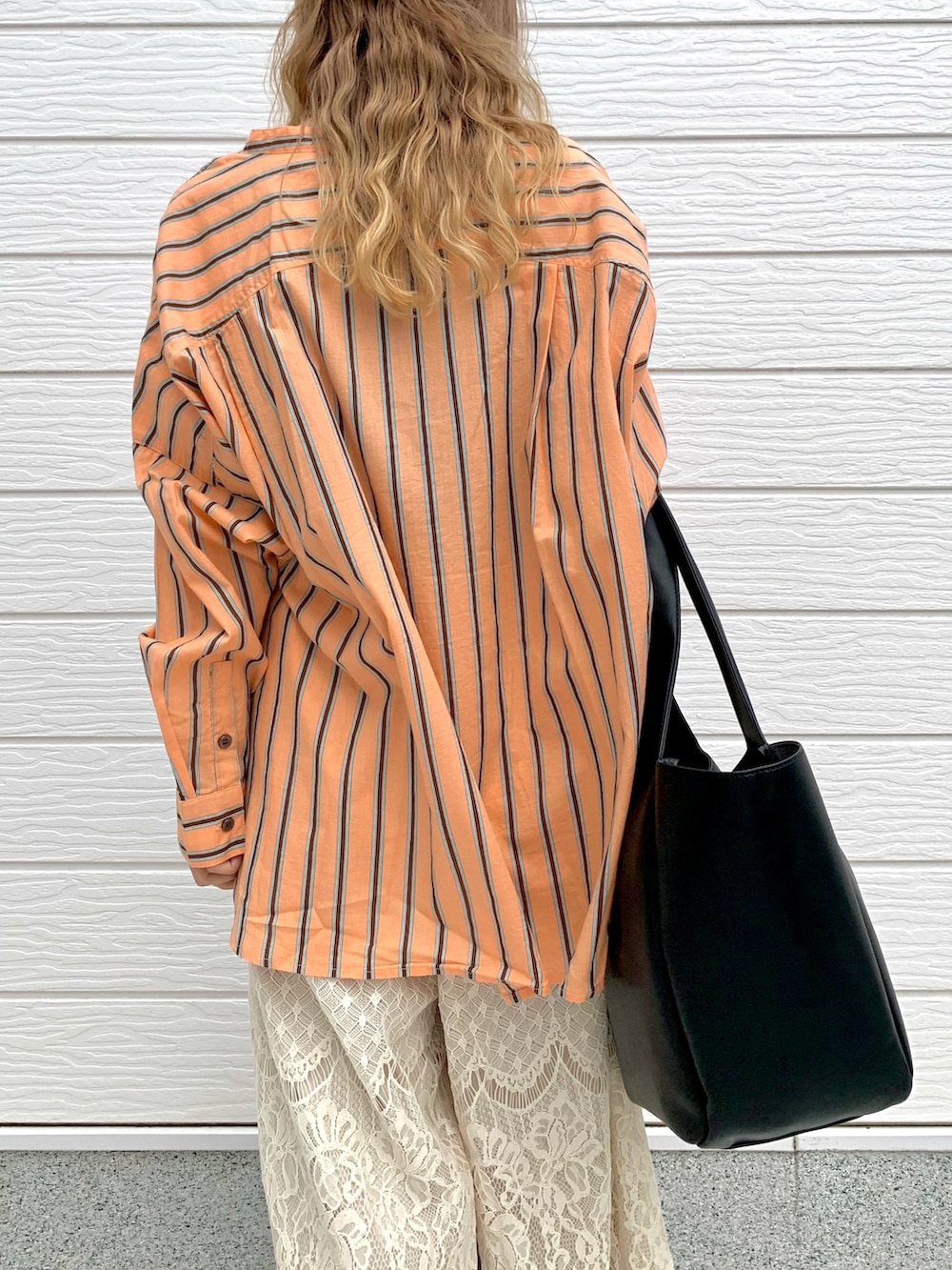 オレンジ系のシャツ/ブラウス、ホワイト系のその他パンツ、ブラック系のトートバッグを着用したレディースの夏コーディネートの5枚目の写真