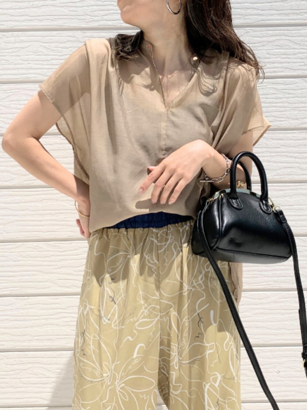 ブラウン系のサンダル、ベージュ系のその他パンツ、ブラック系のショルダーバッグを着用したレディースの春コーディネートの3枚目の写真