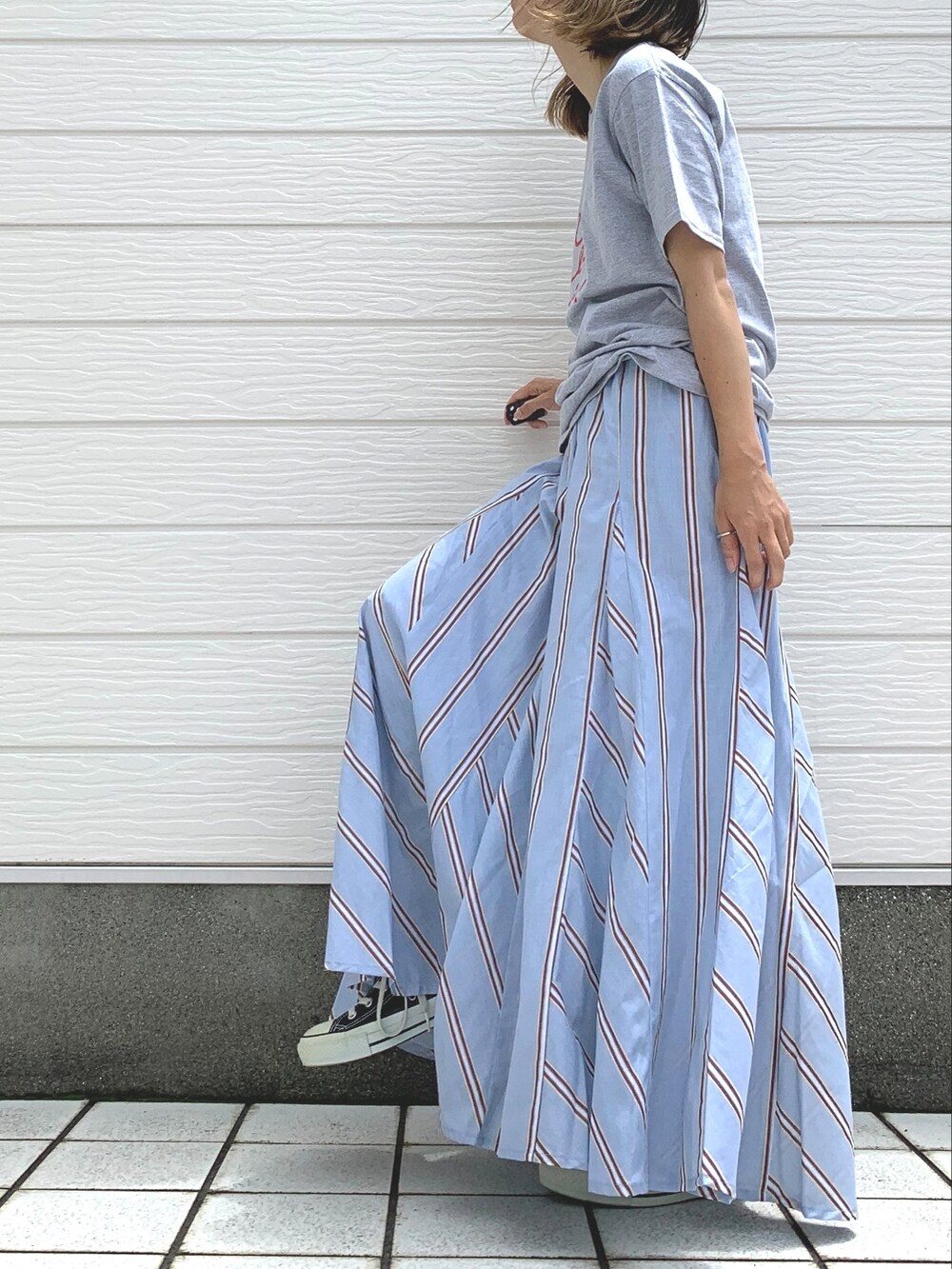 ブラック系のスニーカー、ブルー系のスカート、グレー系のTシャツ/カットソーを着用したレディースの夏コーディネートの2枚目の写真