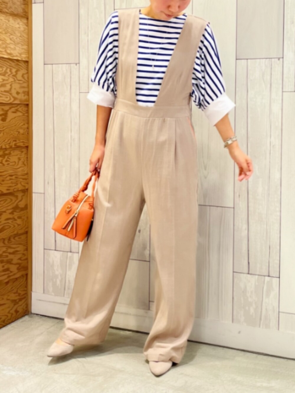 オレンジ系のハンドバッグ、ベージュ系のサロペット/オーバーオール、ブルー系のTシャツ/カットソーを着用したレディースの夏コーディネートの2枚目の写真