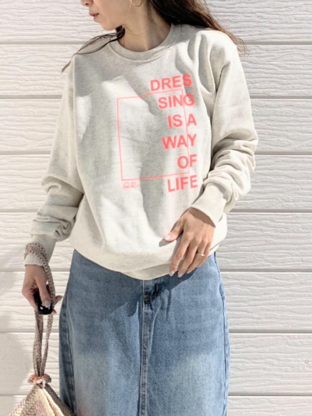 ベージュ系のスウェット、ブルー系のデニムスカート、ホワイト系のスニーカーを着用したレディースの春コーディネートの4枚目の写真