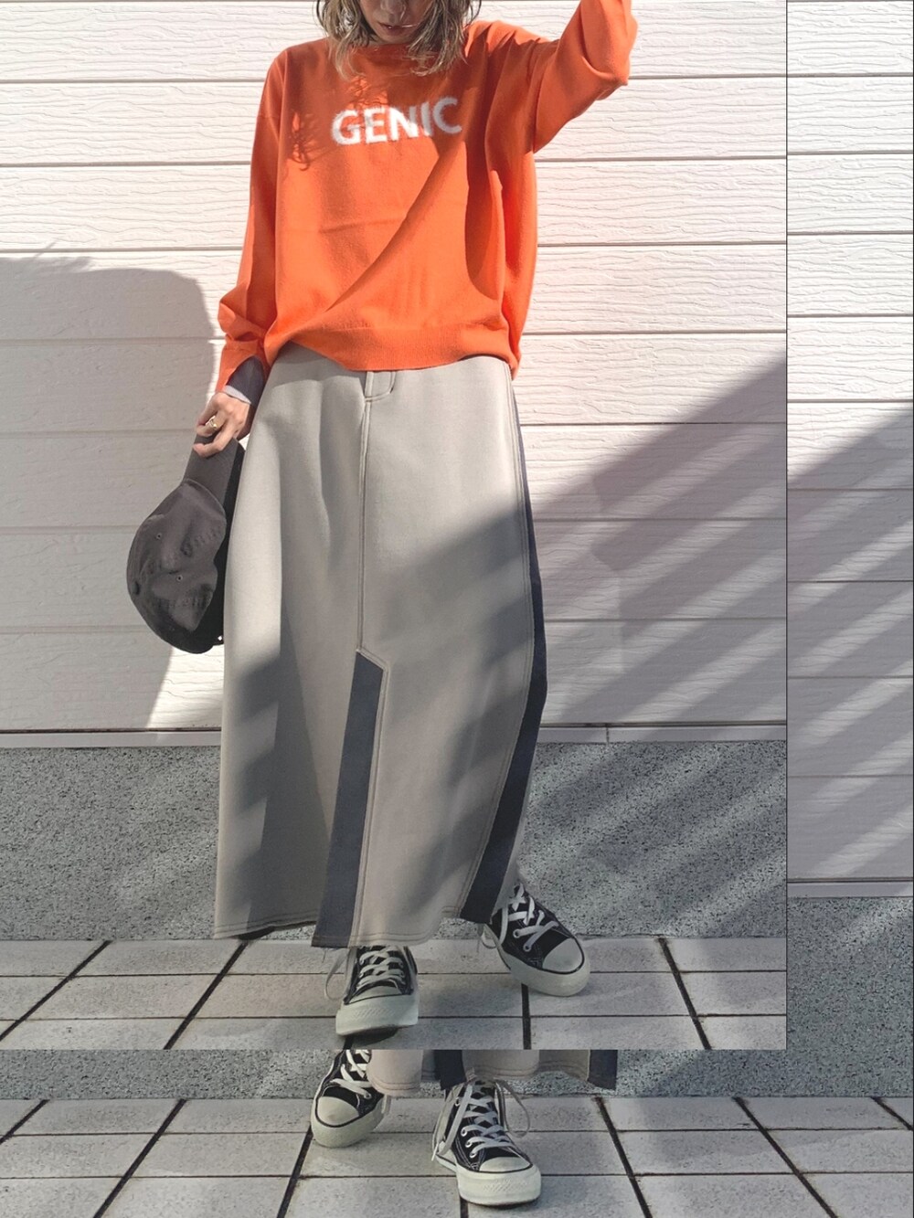 ベージュ系のスカート、オレンジ系のニット/セーター、ブラック系のスニーカーを着用したレディースの冬コーディネートの2枚目の写真