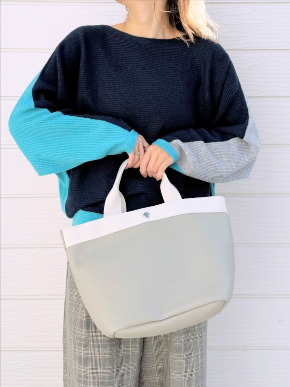 グレー系のトートバッグ、ブルー系のニット/セーター、ベージュ系のスラックスを着用したレディースの冬コーディネートの3枚目の写真