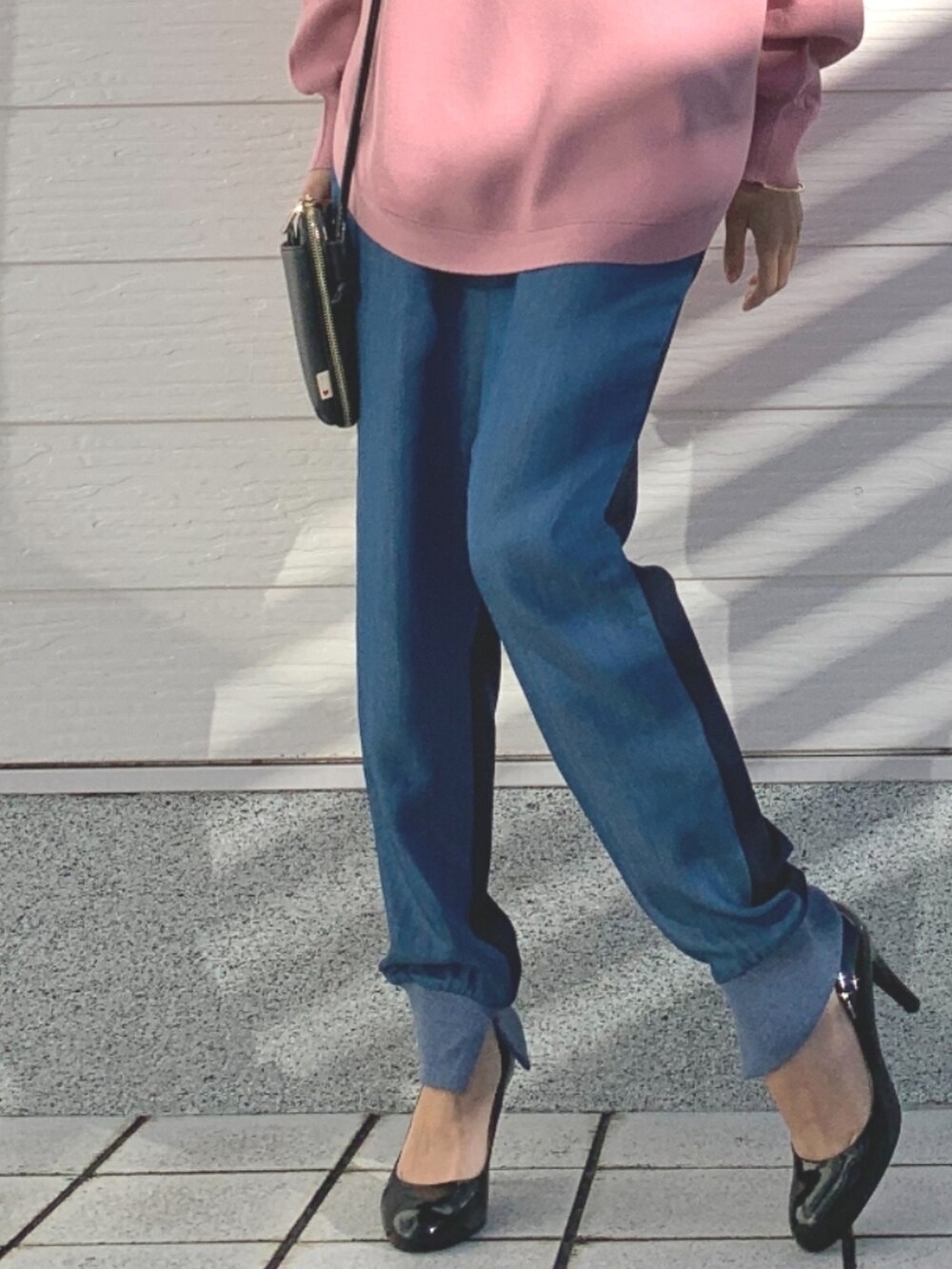 ブルー系のデニムパンツ、ブラック系のショルダーバッグ、ピンク系のニット/セーターを着用したレディースの冬コーディネートの5枚目の写真