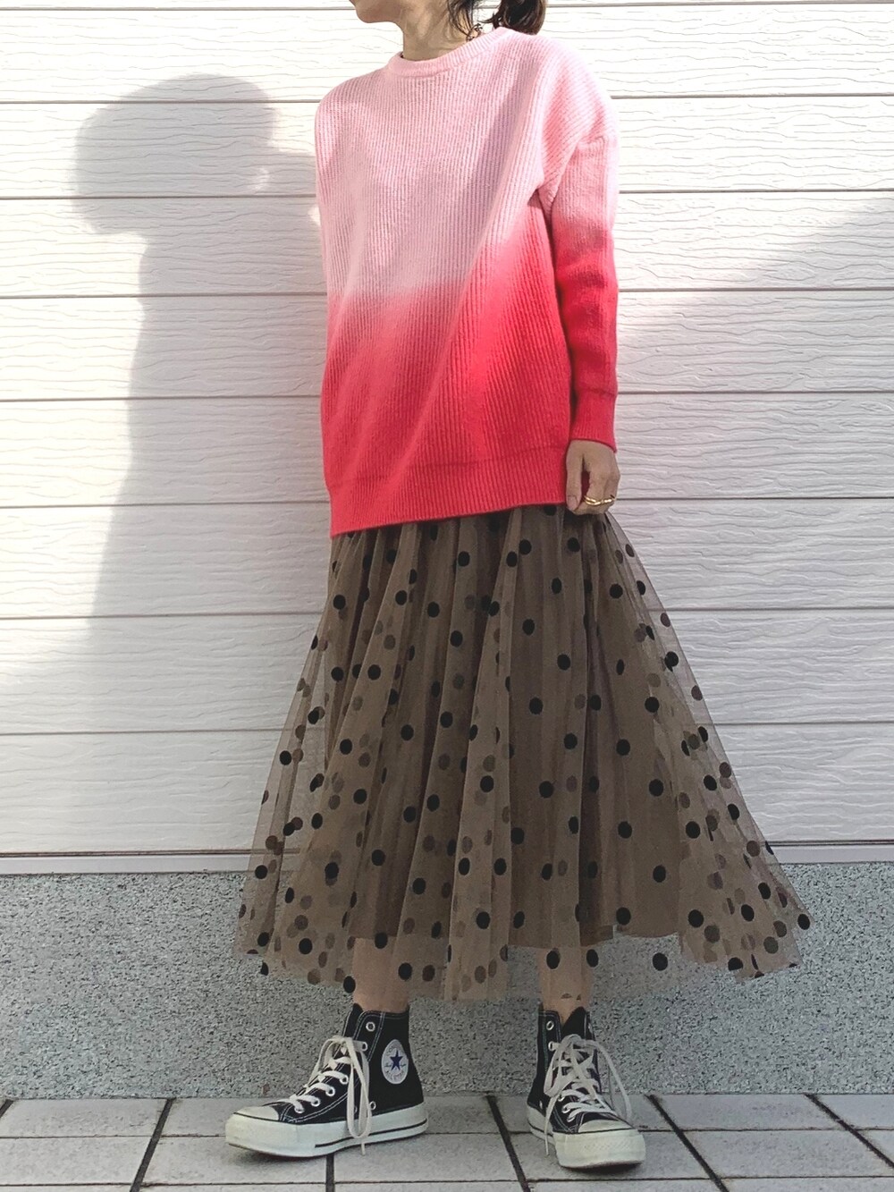 ピンク系のニット/セーター、ブラウン系のスカート、ブラック系のスニーカーを着用したレディースの冬コーディネートの2枚目の写真