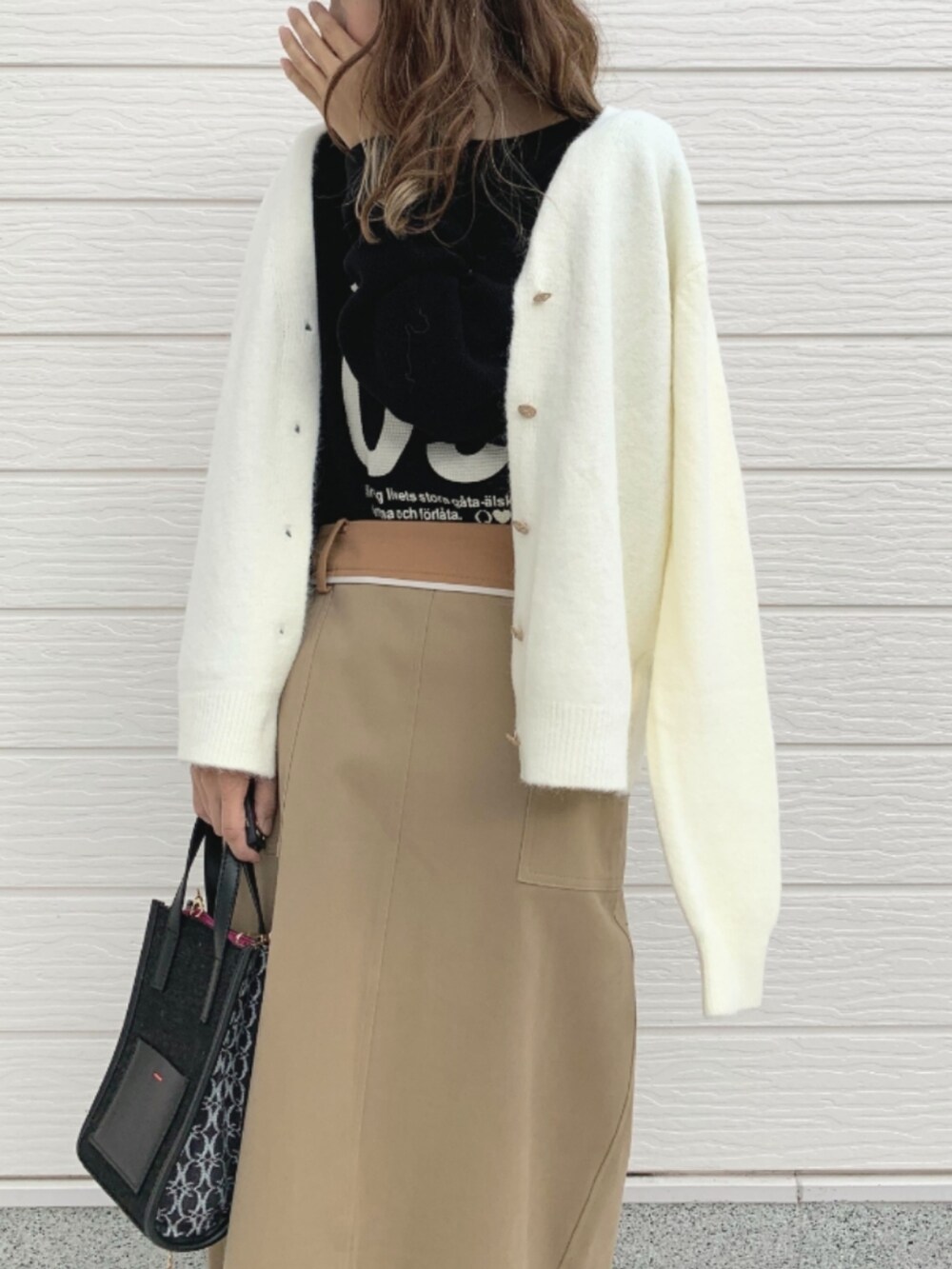 ブラック系のショルダーバッグ、ベージュ系のスカート、ブラック系のTシャツ/カットソーを着用したレディースの秋コーディネートの3枚目の写真