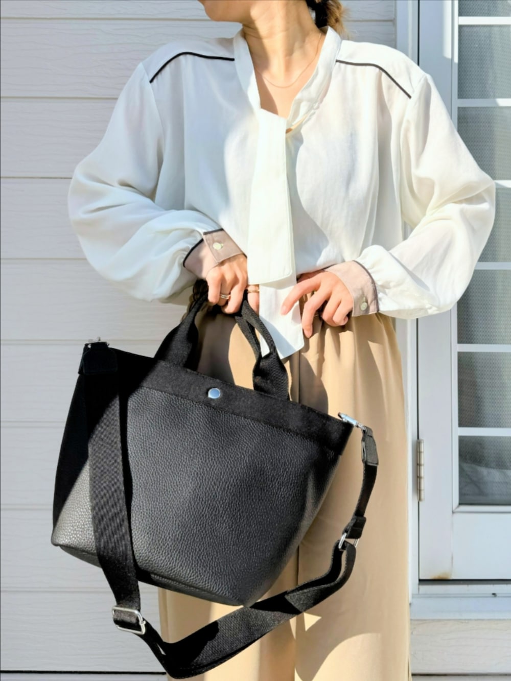 ブラック系のトートバッグ、ベージュ系のその他パンツ、ホワイト系のシャツ/ブラウスを着用したレディースの冬コーディネートの4枚目の写真