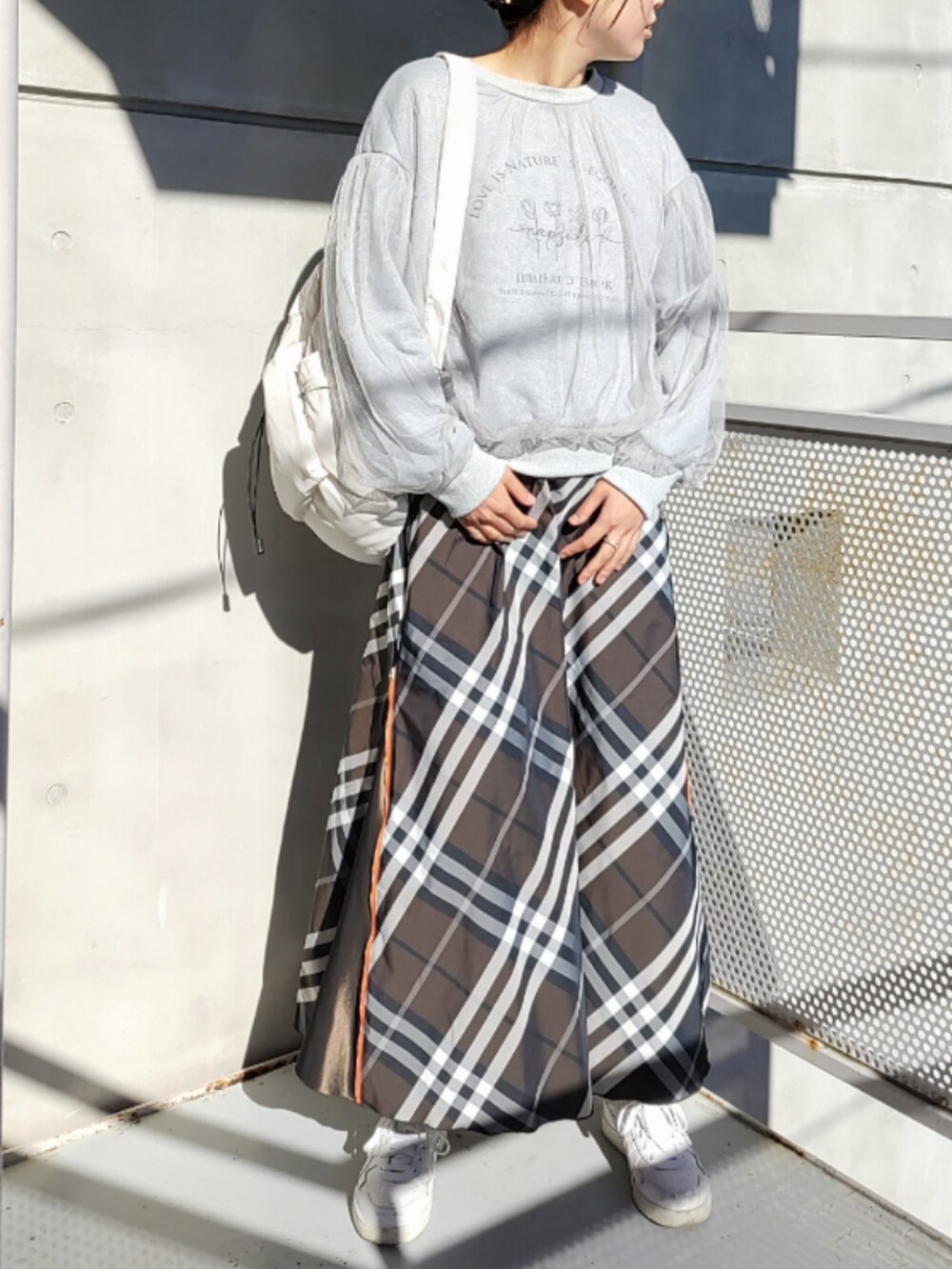 ホワイト系のバックパック/リュック、ブラウン系のスカート、ホワイト系のスニーカーを着用したレディースの秋コーディネートの2枚目の写真