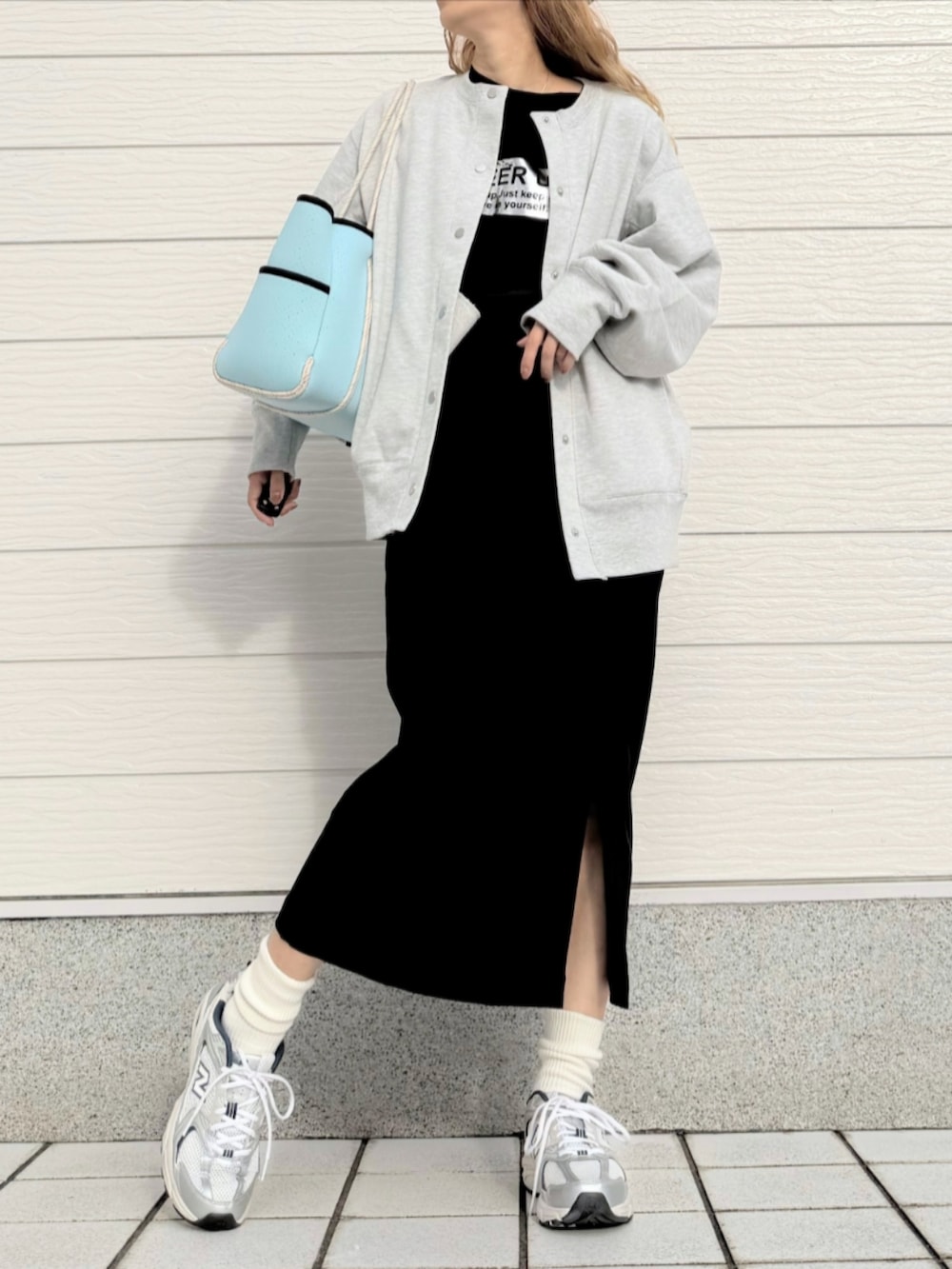 シルバー系のスニーカー、ブラック系のスカート、ブルー系のトートバッグを着用したレディースの秋コーディネートの2枚目の写真