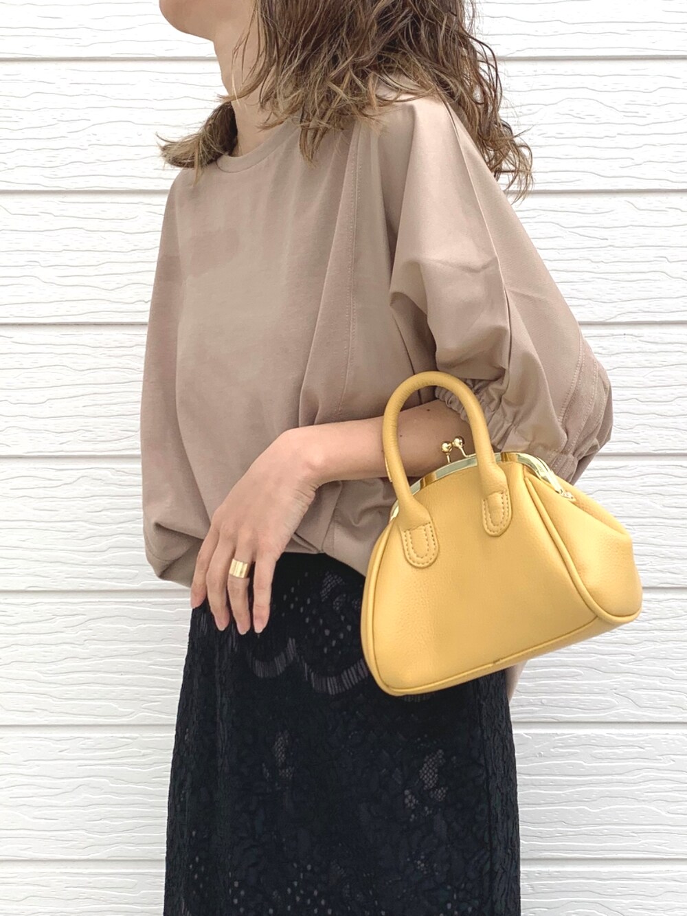 イエロー系のショルダーバッグ、ブラック系のスカート、イエロー系のTシャツ/カットソーを着用したレディースの春コーディネートの4枚目の写真