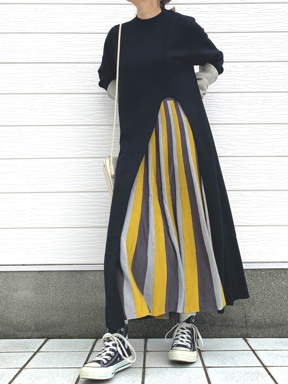 ブラック系のスニーカー、イエロー系のスカート、ホワイト系のショルダーバッグを着用したレディースの秋コーディネートの2枚目の写真